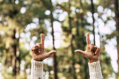 Cropped hands of woman against trees