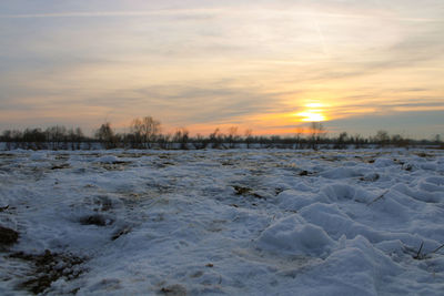 Snow covered land during sunset