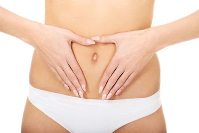 Midsection of woman touching hair over white background