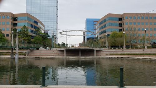 Buildings by lake against sky in city