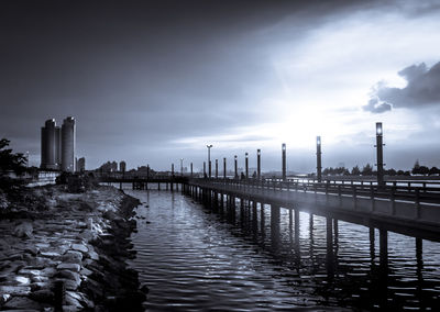 Pier over sea against sky in city