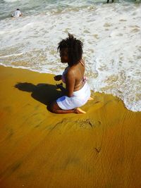 Young woman kneeling on shore at beach