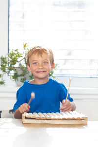 Smiling boy playing xylophone on table