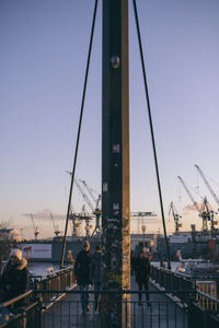 People at commercial dock against clear sky during sunset