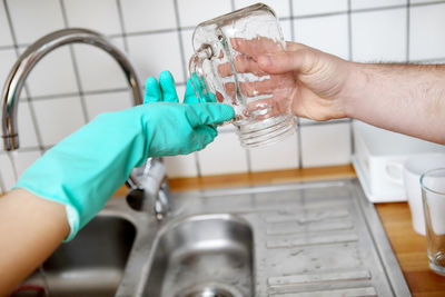 Cropped image of person holding hands with water in bathroom