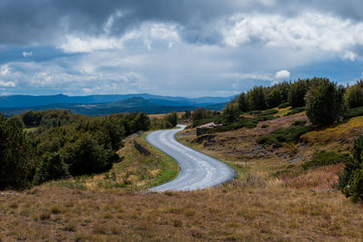 Scenic view of road by mountains against sky