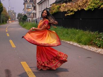 Portrait of smiling woman in sari dancing on road