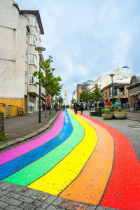 Street by multi colored houses against sky in city