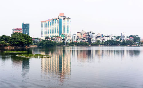 Reflection of buildings in lake against clear sky