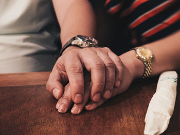 Cropped image of couple holding hands on table