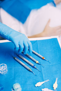 Cropped hand of dentist picking dental equipment on table