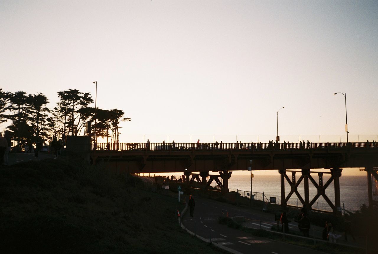 SILHOUETTE PEOPLE ON BRIDGE AGAINST SKY DURING SUNSET