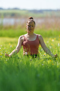 Woman doing yoga poses outdoors in summer near lake