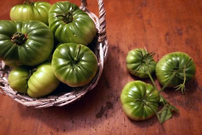 High angle view of fresh green tomatoes in basket and table