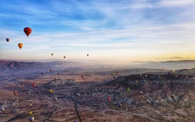 Hot air balloons flying over landscape against sky