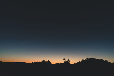 Silhouette landscape against clear sky at night