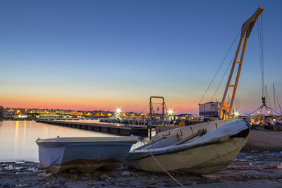 Boats moored at harbor against clear sky