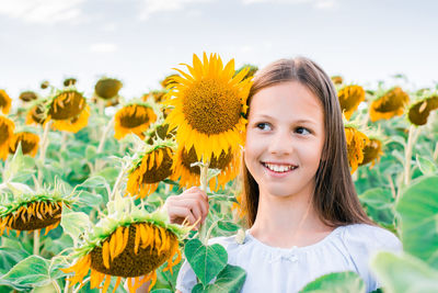 Smiling girl in a field of sunflowers in the sun. local tourism and freedom