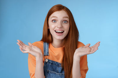 Portrait of smiling young woman against blue background