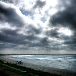 Scenic view of beach against cloudy sky