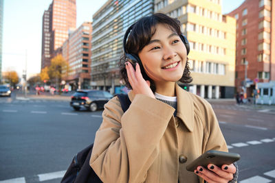 Portrait of young woman standing in city