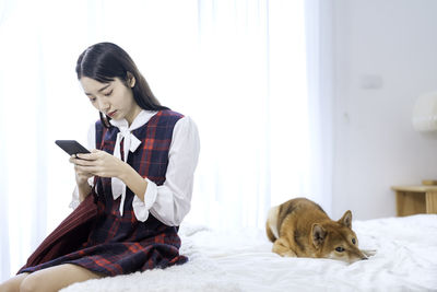 The girl uses a smart phone to feel hurt the dog because she doesn't care. roommates ignoring each.