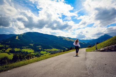 Rear view of woman walking on road against mountains