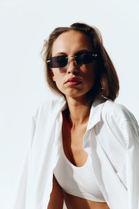 Young woman wearing sunglasses against white background