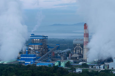 Smoke emitting from factory against sky