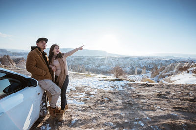 Rear view of man with arms outstretched standing on snow