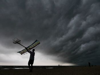 Low angle view of man standing on street against storm clouds