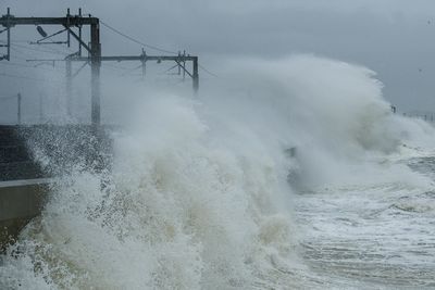 Waves splashing on shore against sky