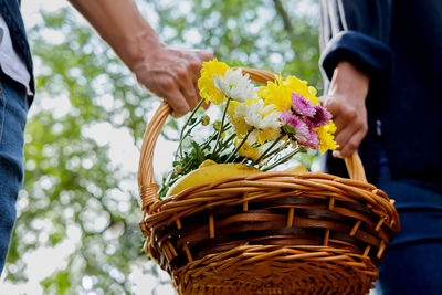 Close-up of people holding flowers in basket