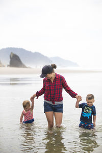 Mother wades through water with her two kids.