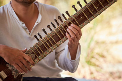 Midsection of man playing guitar