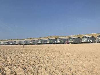 View of beach against buildings against clear blue sky