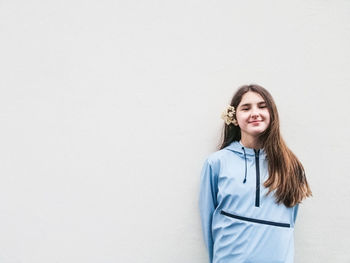 Portrait of smiling young woman standing against white background