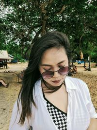 Portrait of young woman wearing sunglasses standing against plants