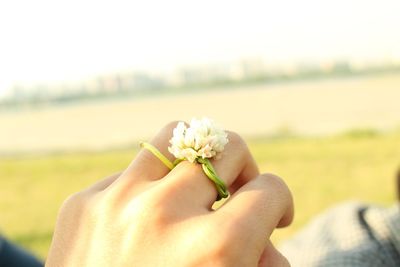 Close-up of hand holding white flower on field