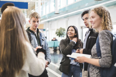 Young male and female students talking while standing in cafeteria at university