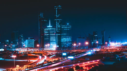 Illuminated city street and buildings against sky at night