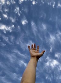 Low angle view of human hand against sky