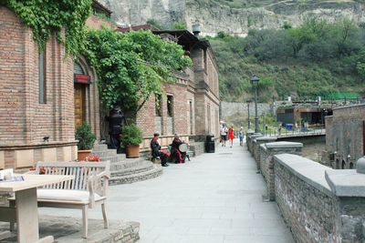 People on footpath amidst buildings in city