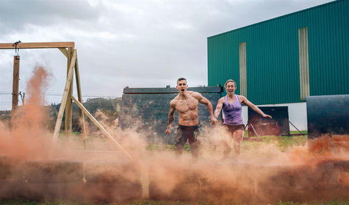 Shirtless man with woman running outdoors