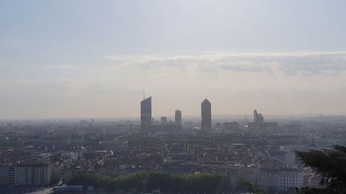 Aerial view of buildings in city against cloudy sky