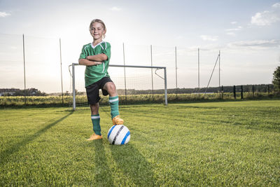 Portrait of confident young football player with ball on football ground