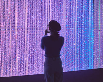 Rear view of silhouette woman standing against illuminated lights