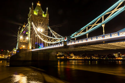 Illuminated bridge over river at night