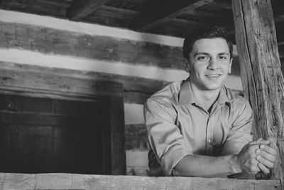 Portrait of smiling young man standing in log cabin