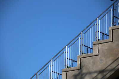 Low angle view of staircase by building against clear blue sky